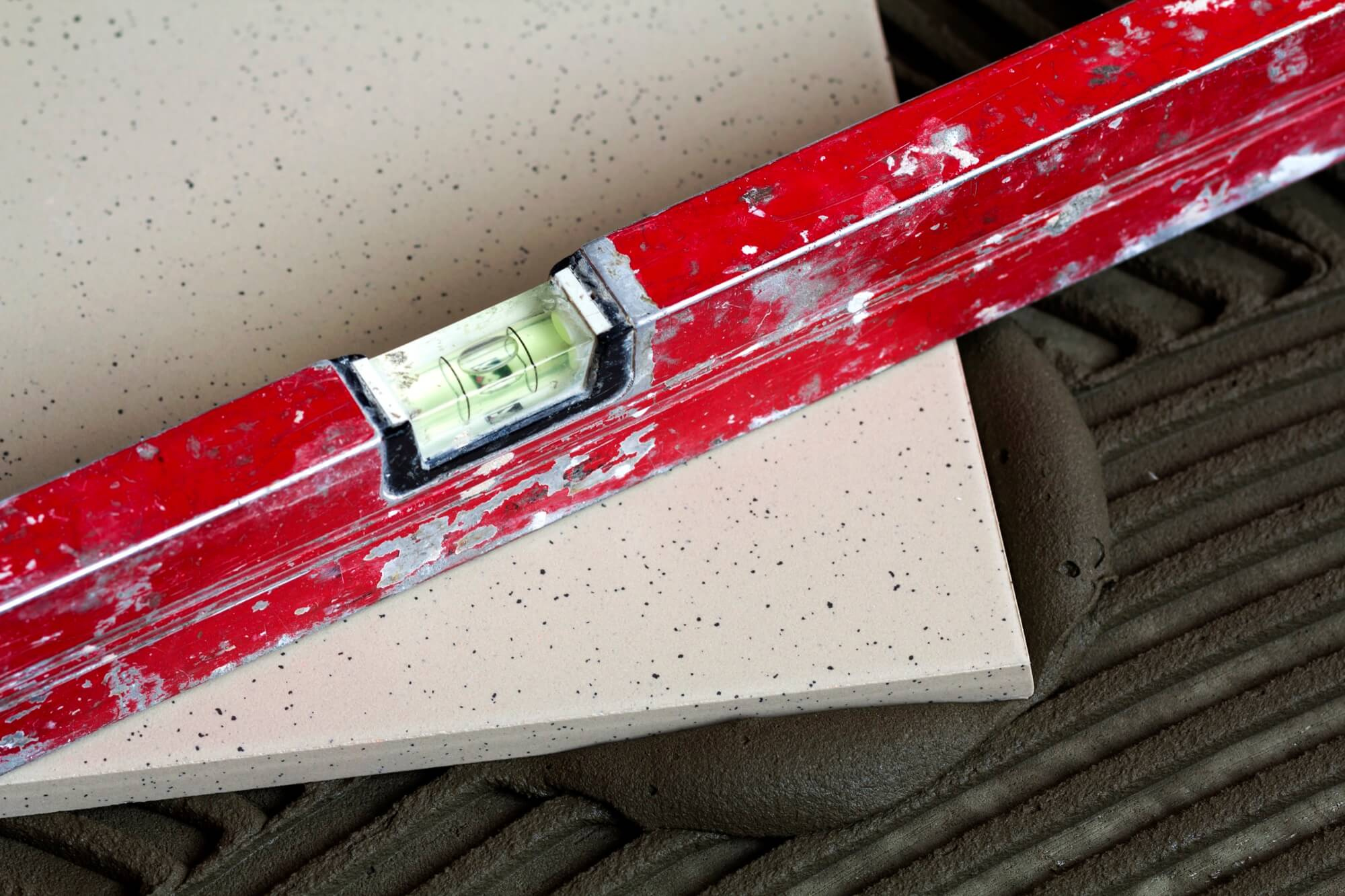 Närbild på klinkerläggning med vattenpass och fix under badrumsrenovering.